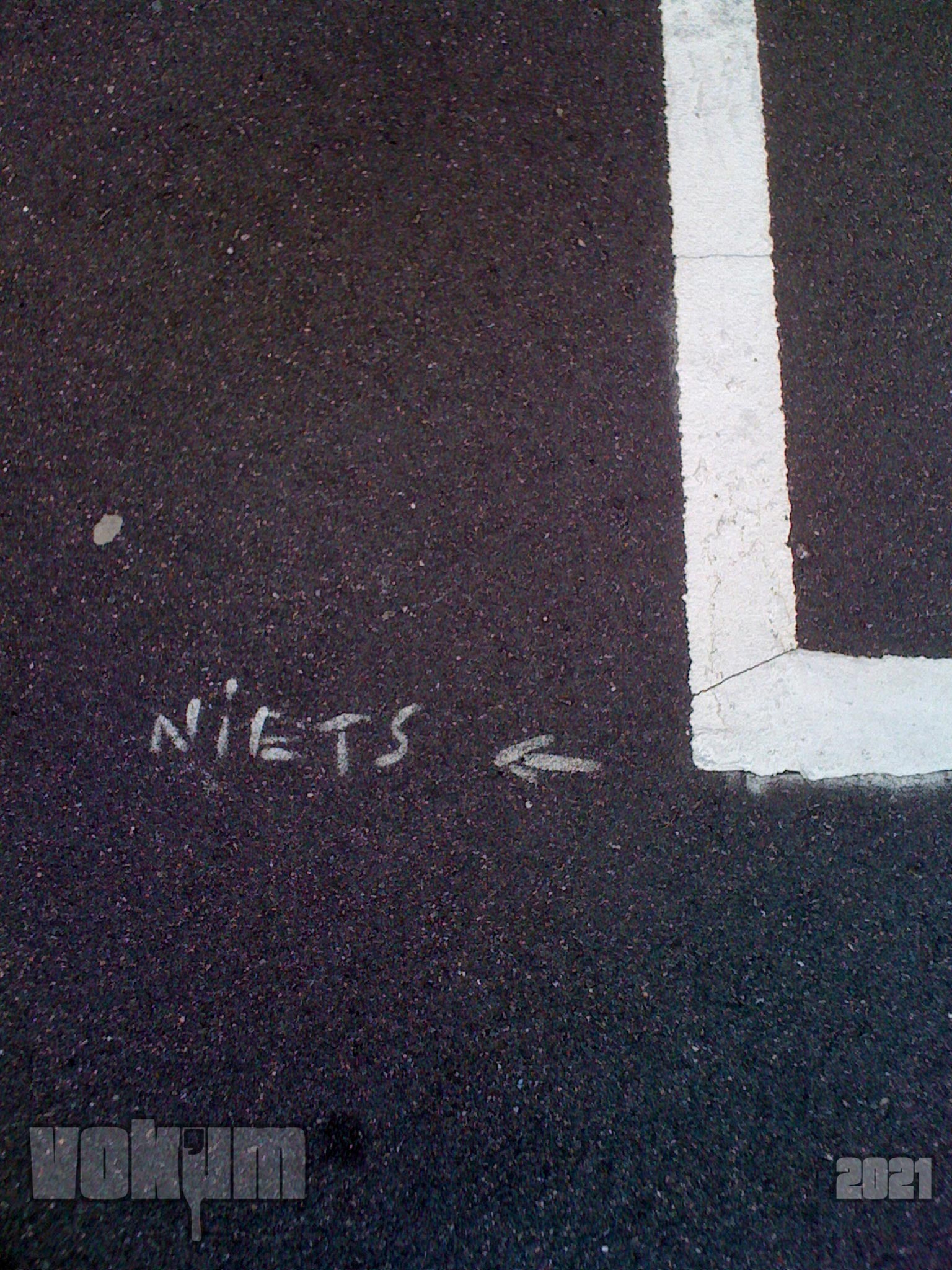The word 'niets' (nothing in Dutch) written on the tarmac. And an arrow pointing to the word and away from the outline of a parking spot.